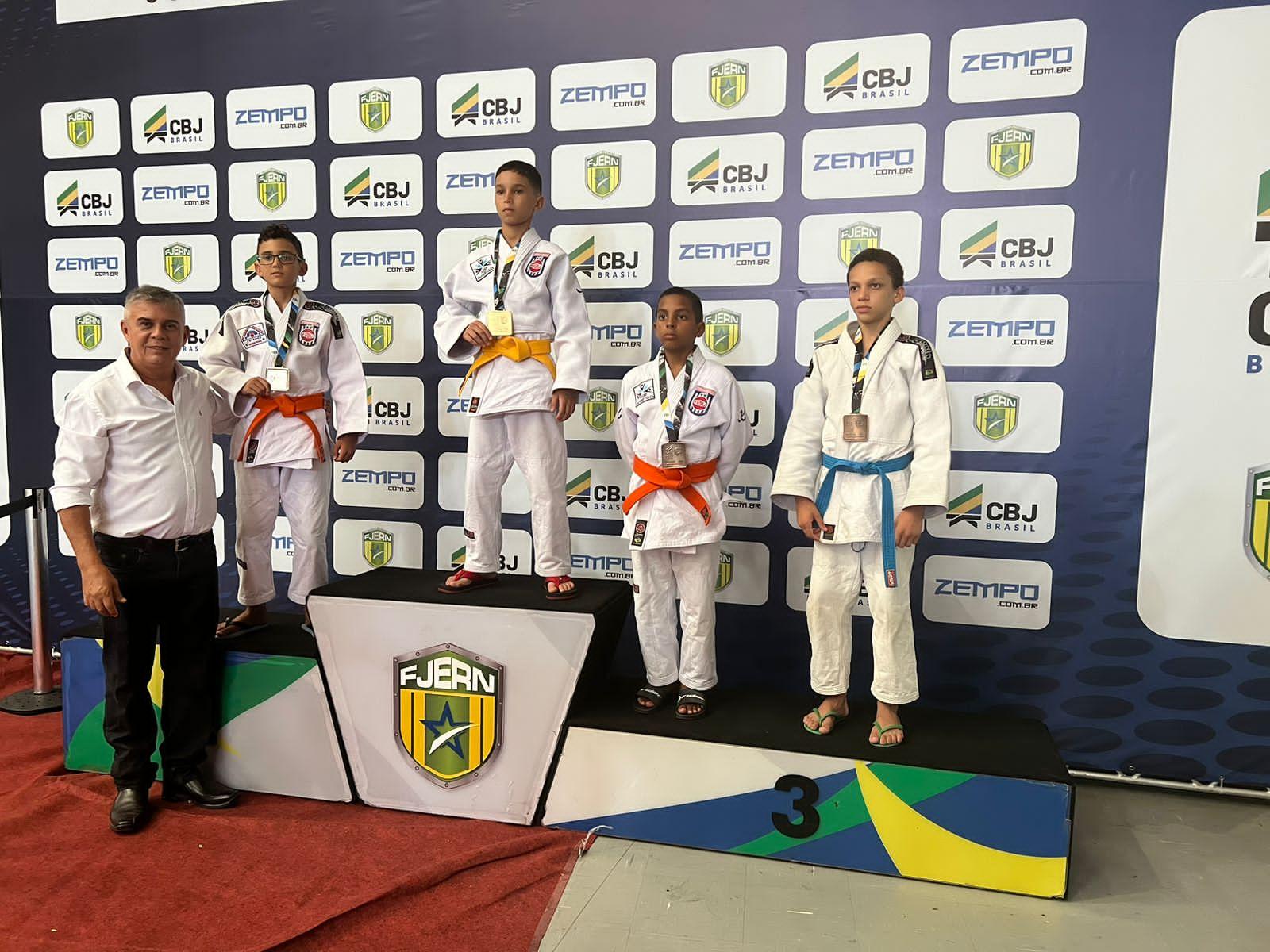 Crianças em pé em um pódio segurando medalhas