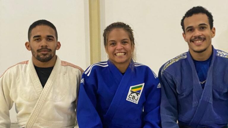 Três atletas com kimono sorrindo